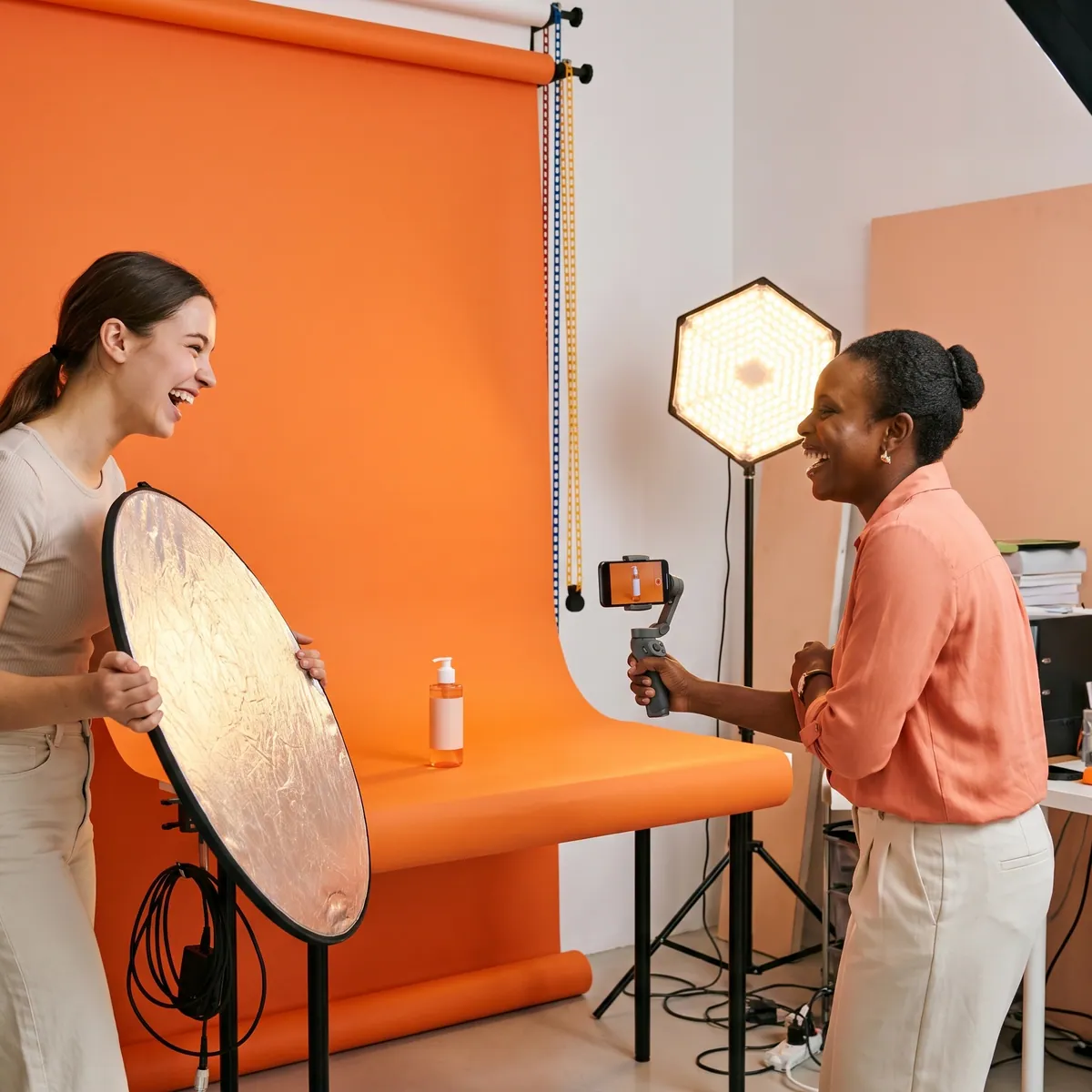 Une créatrice qui filme un produit pour une publication programmée sur un fond mandarine
